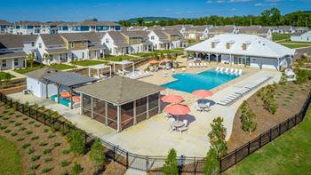 an aerial view of a swimming pool and patio area with umbrellas and houses